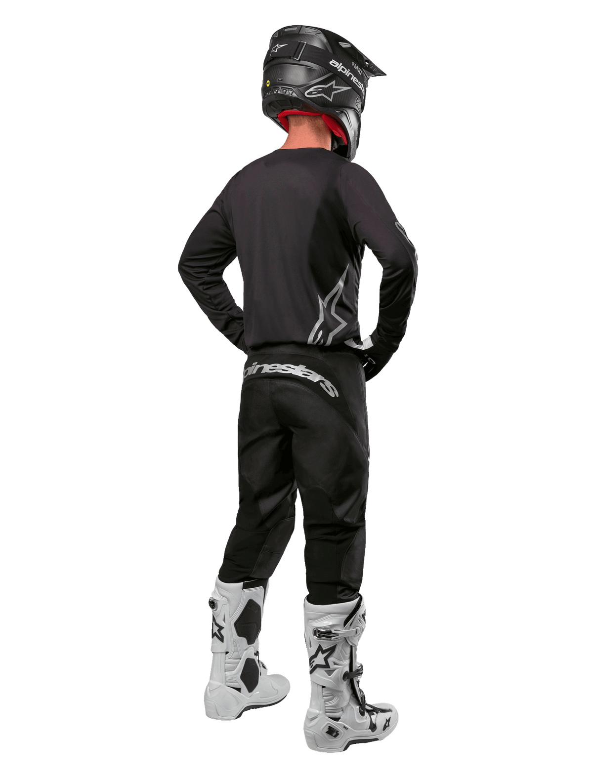 Alpinestars 2024 Fluid Graphite Gear Set, motorcrossrijder van achteren gezien, grafietgrijze jersey en broek met zilveren Alpinestars-logo's, zwarte helm en witte motorcrosslaarzen, atletische pasvorm voor off-road rijden