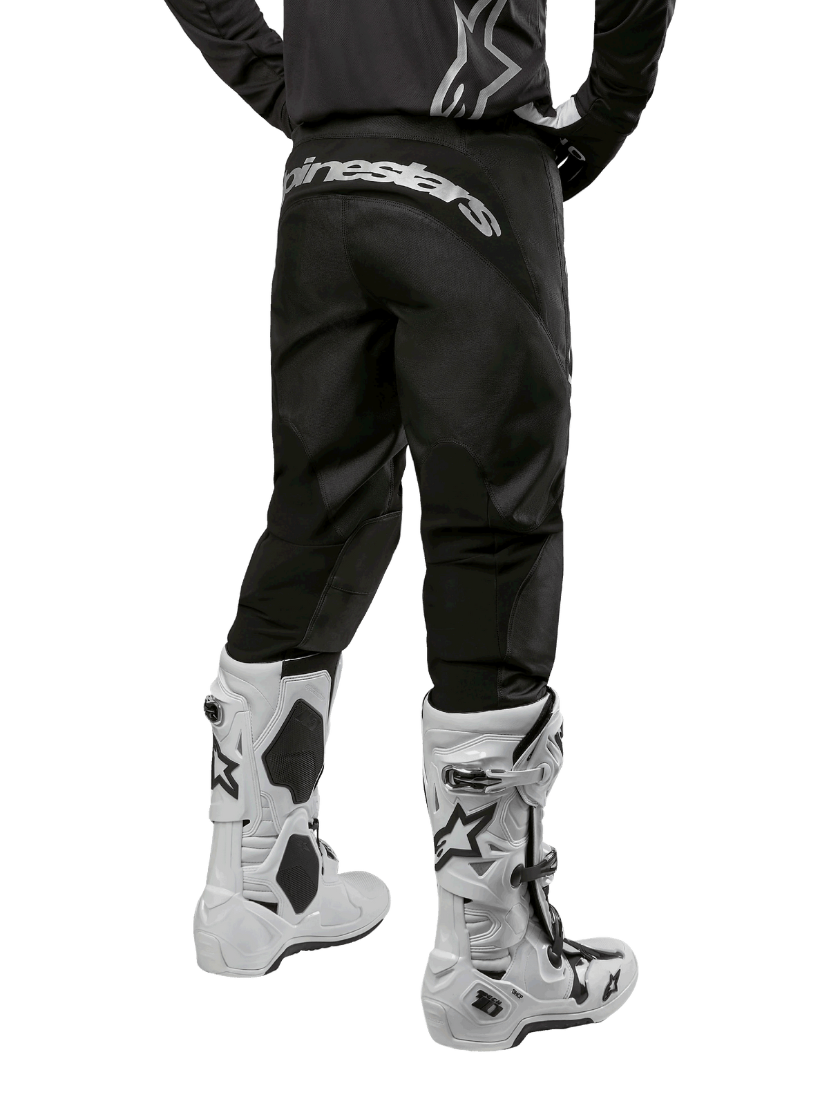 Alpinestars 2024 Fluid Graphite Gear Set, achteraanzicht van zwarte en grijze motorcrossbroek met wit Alpinestars logo op het zitvlak, gedragen met witte en zwarte motorcrosslaarzen, gespecialiseerde off-road race-uitrusting