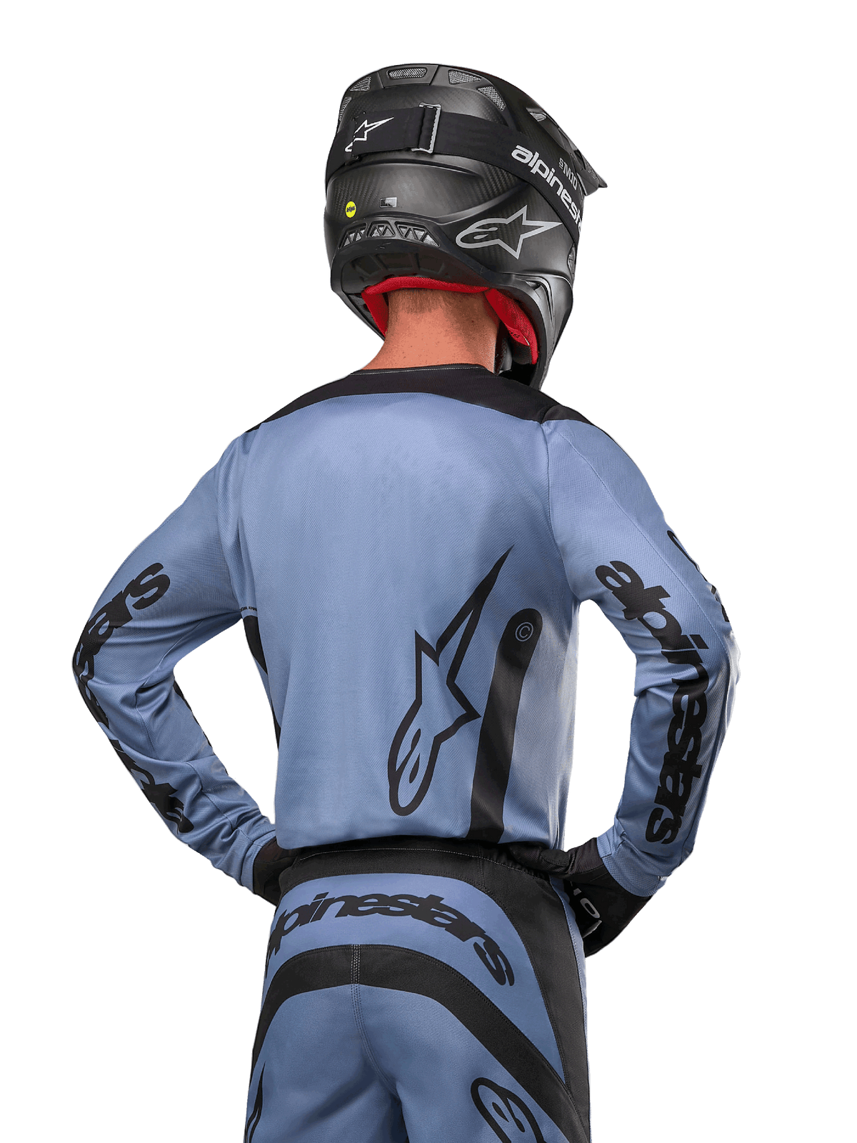 Alpinestars 2024 Fluid Lurv Jersey, motocross shirt, lichtblauw en zwart, achteraanzicht van rijder met groot sterlogo en branding op de mouwen, gedragen met een zwarte helm en bijpassende off-road broek, professionele racekleding