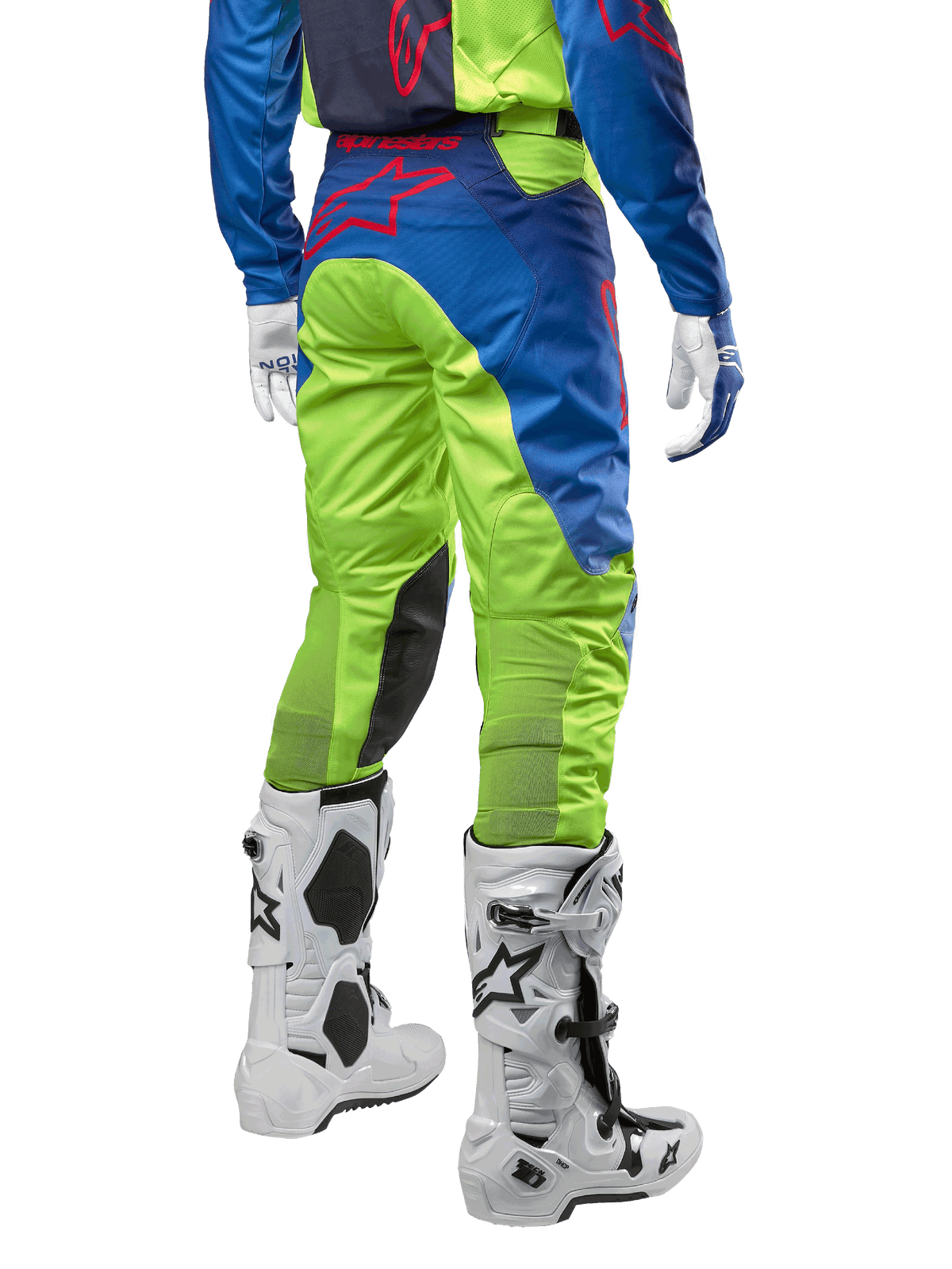 Alpinestars 2024 Racer Hoen crossbroek, motorcross broek, fluoriserend geel en donkerblauw (Blue Night Navy), achteraanzicht, voorzien van een rood Alpinestars-logo, gedragen met bijpassende jersey, witte handschoenen en witte motorcrosslaarzen, duurzaam textiel voor off-road racing