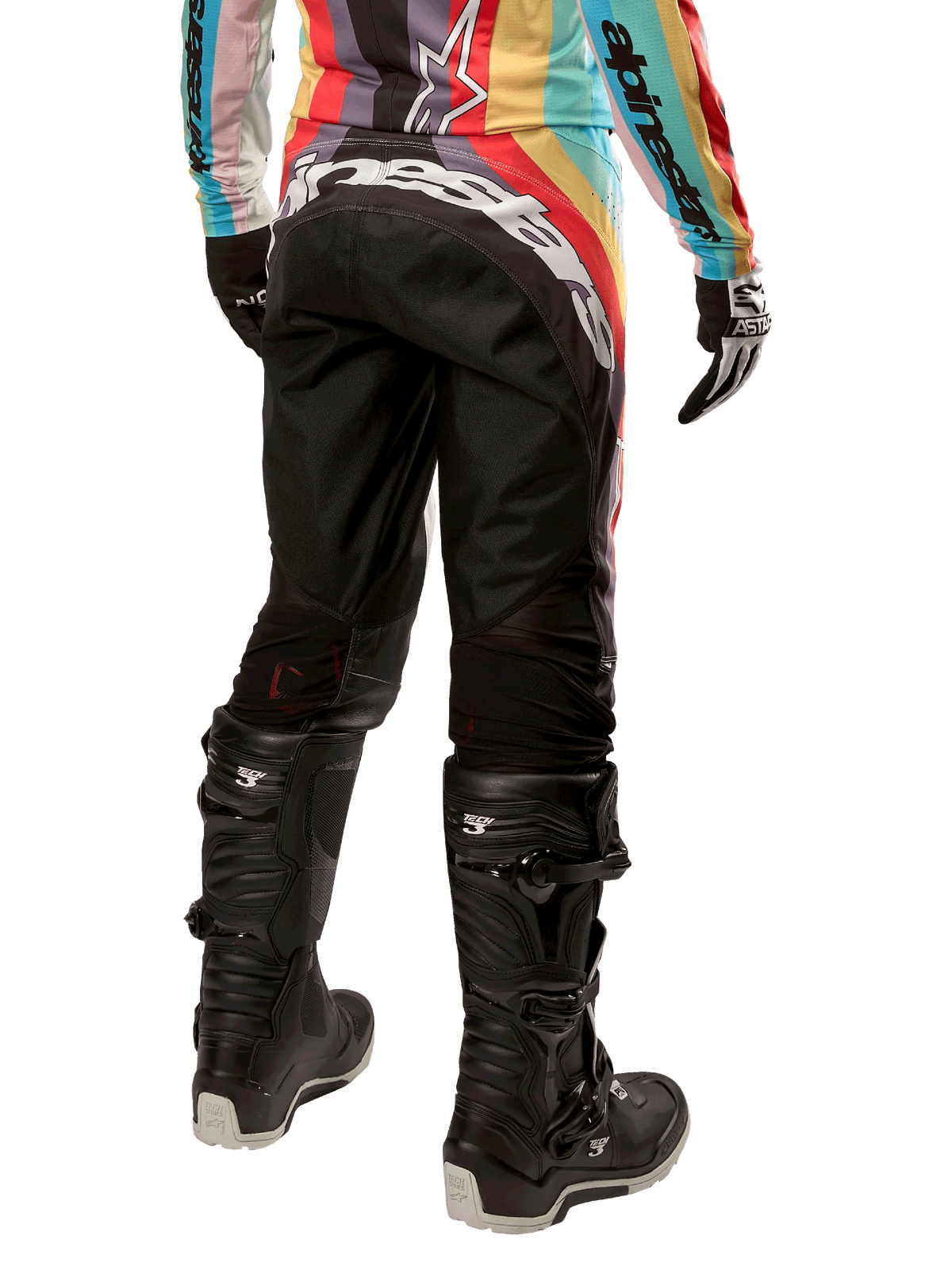 Alpinestars Stella 2024 Techstar dames motorcrossbroek, zwart multicolor, achteraanzicht met opvallende witte branding op het zitvlak, gedragen met zwarte Tech 3-laarzen en een bijpassende multicolor jersey, professionele off-road racekleding.
