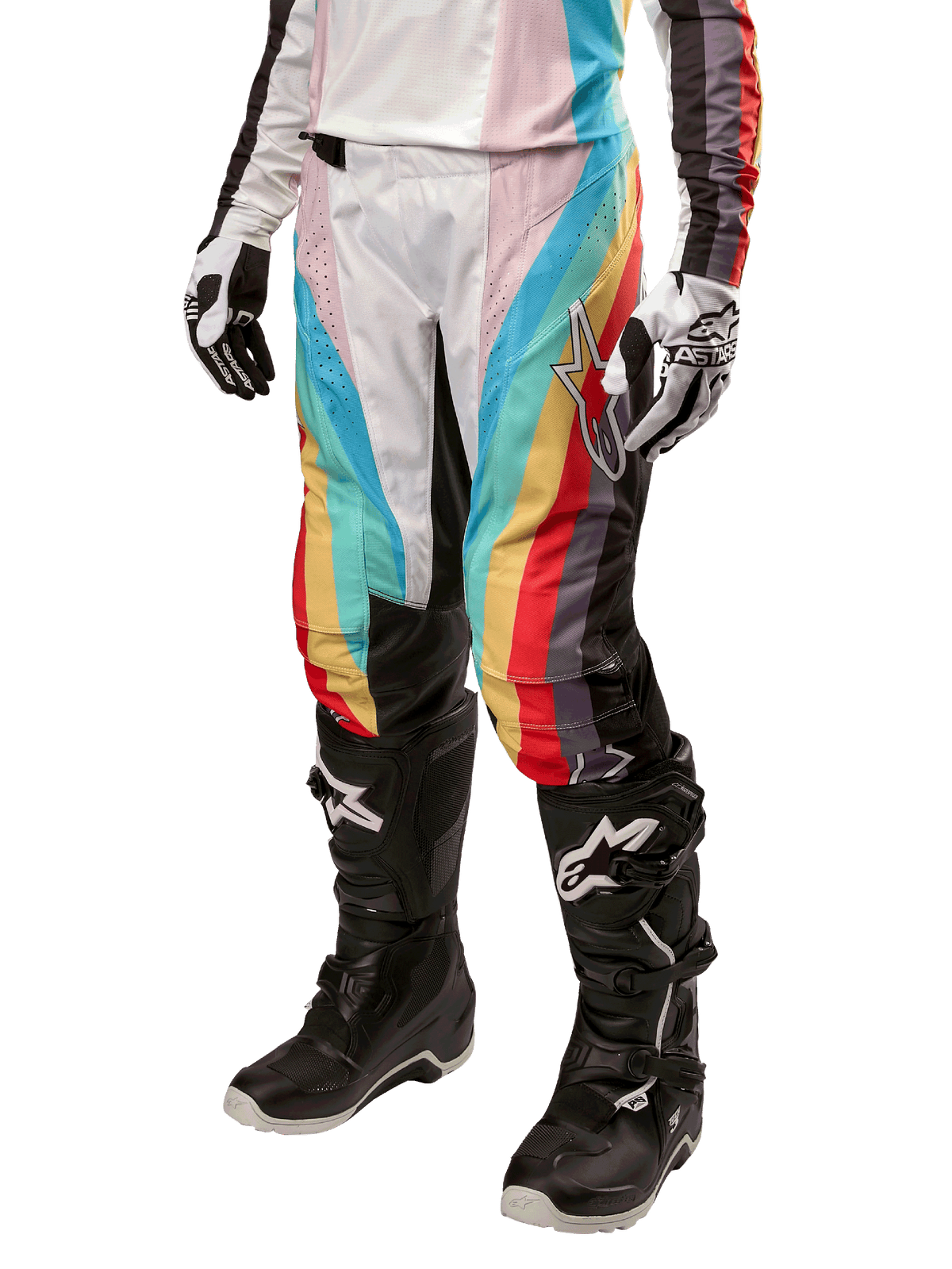 Alpinestars Stella Techstar 2024 damesbroek, motorcrossbroek, zwart multicolor met diagonale rode, gele en blauwe strepen, gedragen met zwarte motorlaarzen en witte handschoenen, met beschermende zwarte kniepanelen en opvallende branding voor off-road racing.