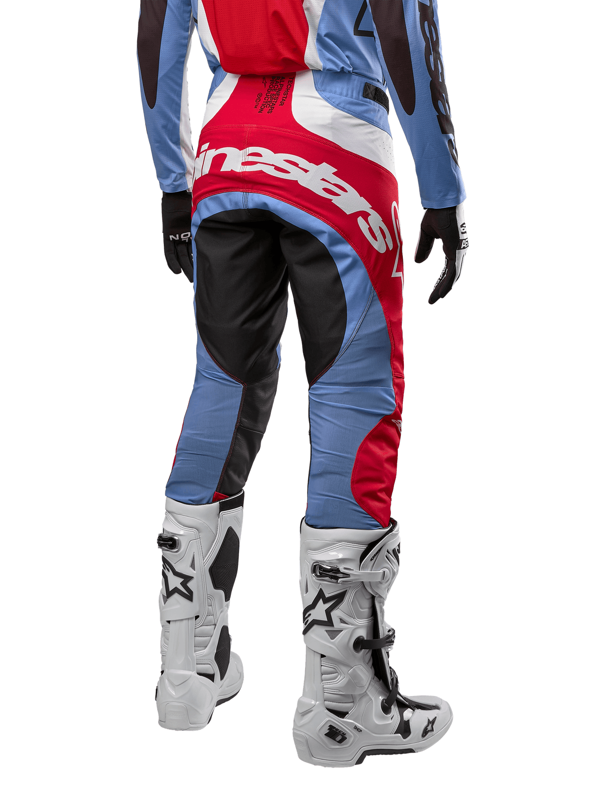 Alpinestars 2024 Techstar Ocuri broek, motorcrossbroek, lichtblauw, marsrood en wit, achteraanzicht met de nadruk op het grote rode Alpinestars-logo op het zitvlak, gedragen met witte motorcrosslaarzen en bijpassende jersey.