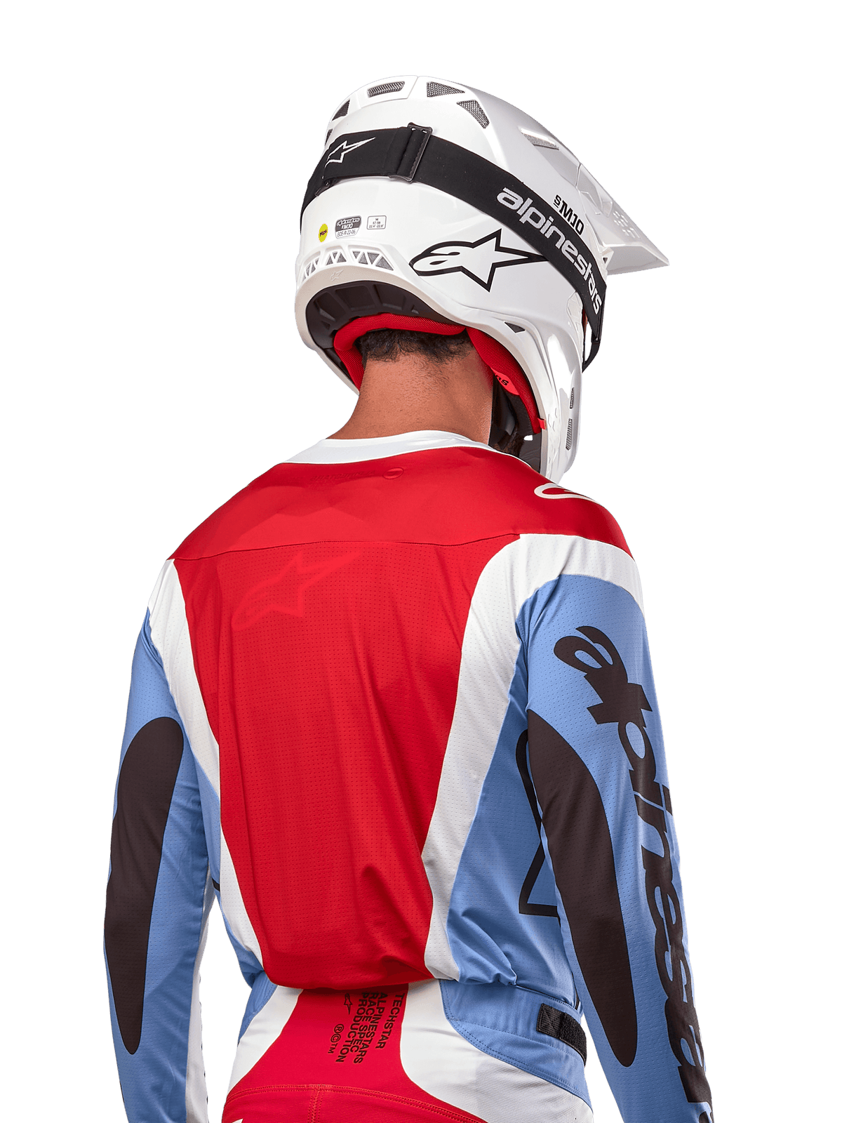 Alpinestars 2024 Techstar Ocuri Jersey, motorcross shirt, lichtblauw, Mars-rood en wit, achteraanzicht van rijder met bijpassende witte helm en zwarte crossbril, voorzien van opvallende zwarte branding op de mouwen en een ergonomische racepasvorm voor off-road prestaties
