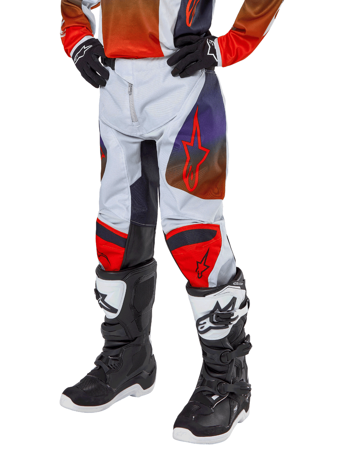 Alpinestars 2024 Youth Racer Hoen Pants, motorcrossbroek, lichtgrijs met feloranje en zwarte accenten, voorzien van rode sterlogo's op de dijen en rode kniepanelen, gedragen met zwart-witte laarzen, duurzaam ontwerp voor off-road racen