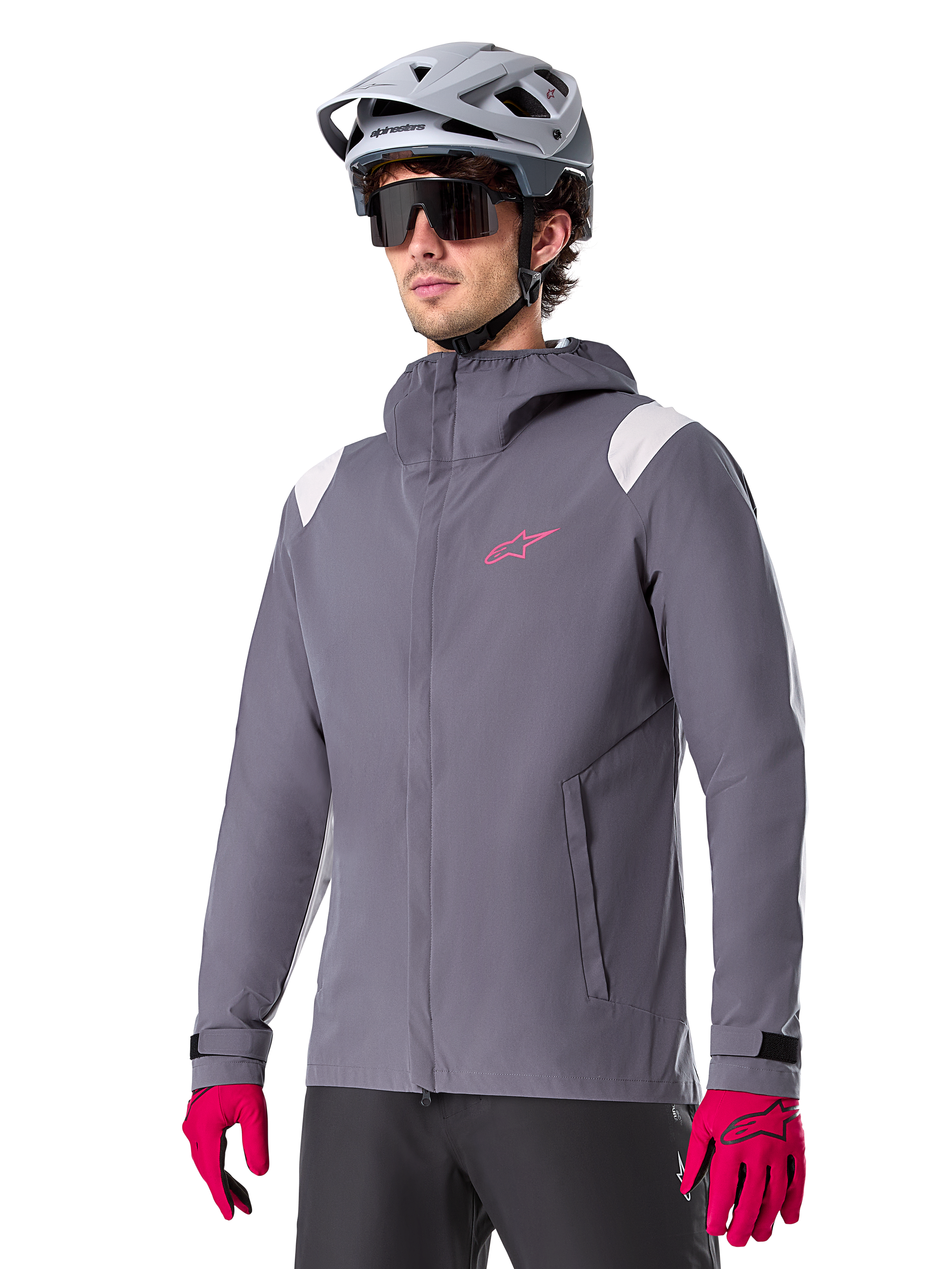 Alpinestars A-Dura Rain Jacket, Mountain Bike Rain Jacket, Dark Titanium Gray with pink logo and white shoulder accents, hooded design with front pockets, worn with pink gloves and a light gray cycling helmet