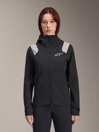 Alpinestars Stella A-Dura regenjas voor dames, MTB-regenjas, zwart met lichtgrijze schouderpanelen, technische shell met capuchon en wit logo op de borst, verstelbare klittenband manchetten, professionele uitrusting voor mountainbiken en rijden in nat weer
