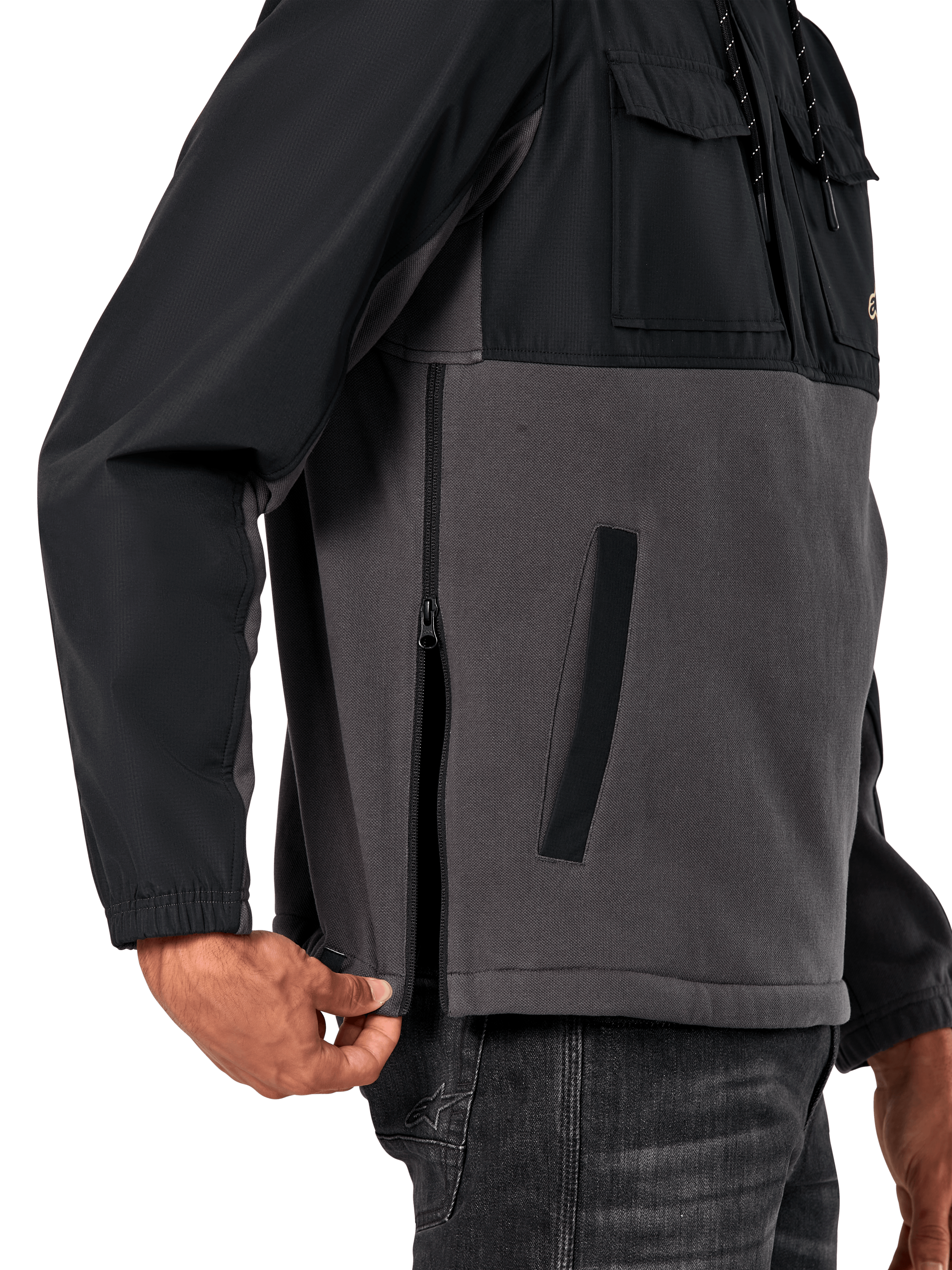 Alpinestars Juncture Hybrid jas in Black Gunmetal, detailweergave van de zijkant met focus op de zijrits en onderste paspelzak, ontwerp van gemengde materialen met grijs canvas fleece en zwarte ripstop overlays, casual op motorsport geïnspireerde streetwear