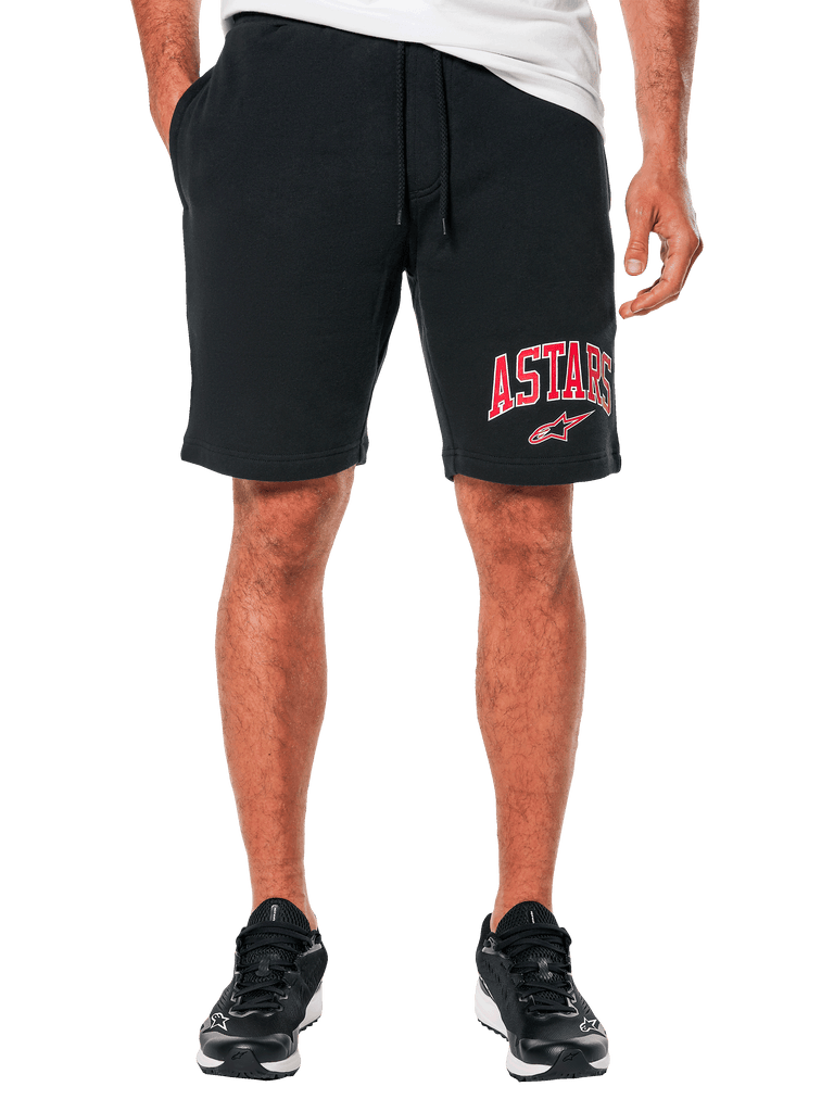 Alpinestars Dunker Short, zwarte fleece trainingshort, rood ASTARS-logo en wit Alpinestars-logo op de pijp, elastische taille met trekkoord, model draagt de short met zwarte sneakers