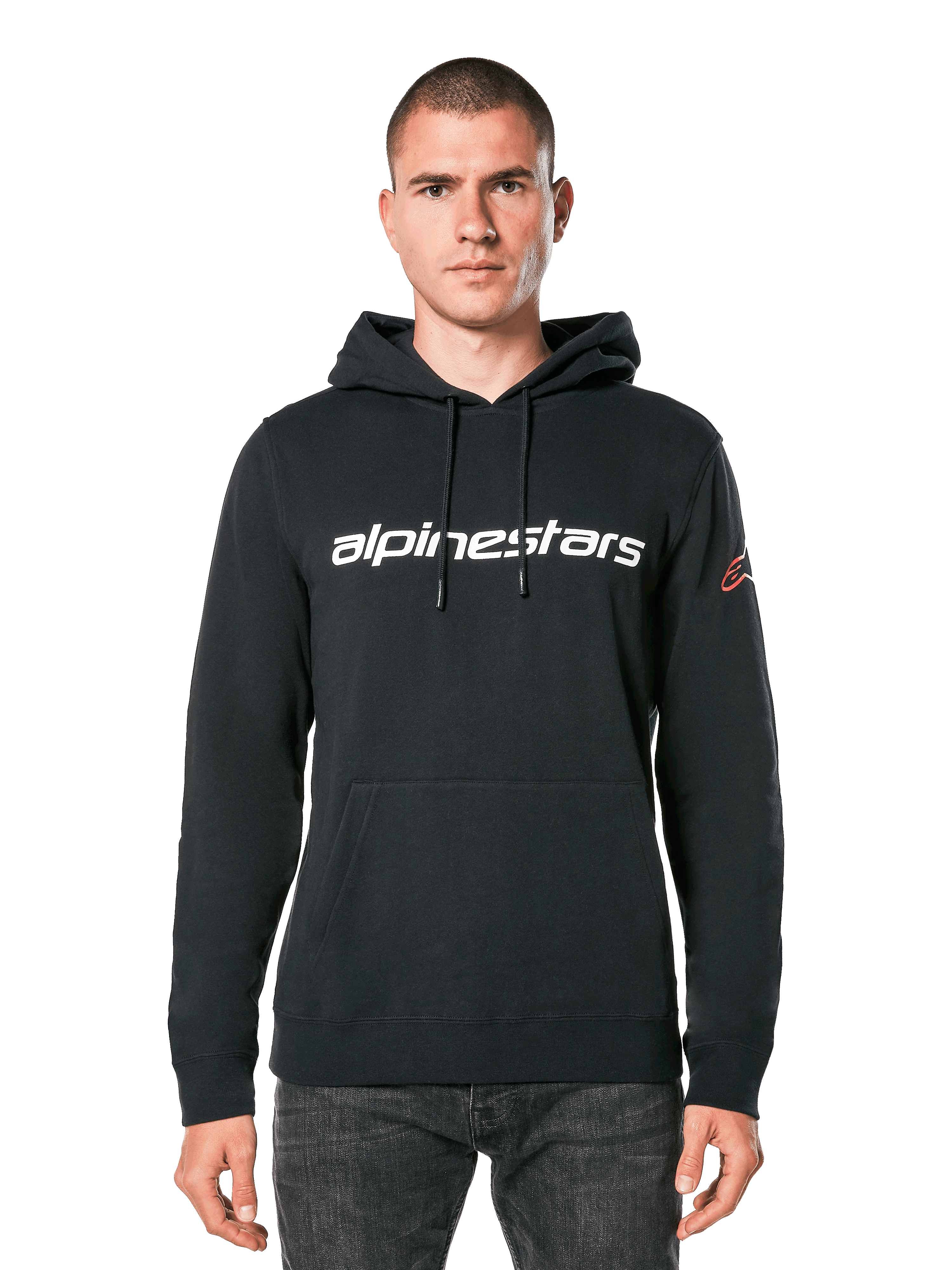 Alpinestars Linear Wordmark V3 hoodie, zwarte pullover hoodie, wit Alpinestars woordmerk op de borst, rood Ageless logo op de mouw, kangoeroezak aan de voorzijde, capuchon met trekkoord, gedragen door een mannelijk model, casual motorsport-geïnspireerde streetwear