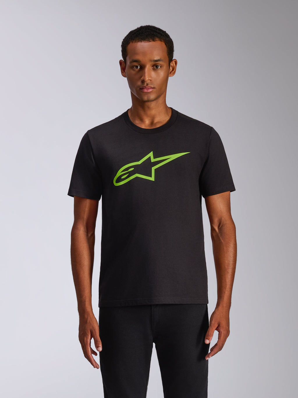 Alpinestars Ageless 2.0 CSF Tee, T-shirt met korte mouwen, zwart met limegroene Alpinestars MX-helm graphic op de borst, casual motorsport streetwear, model draagt het zwarte T-shirt
