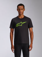 Alpinestars Ageless 2.0 CSF Tee, T-shirt met korte mouwen, zwart met limegroene Alpinestars MX-helm graphic op de borst, casual motorsport streetwear, model draagt het zwarte T-shirt
