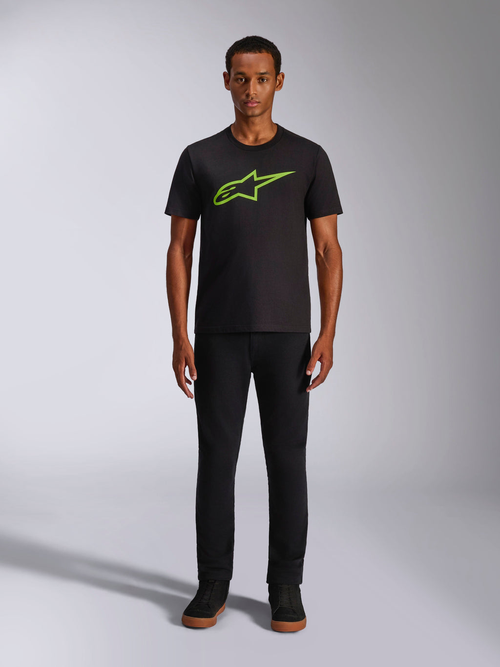 Alpinestars Ageless 2.0 CSF Tee, T-shirt met korte mouwen, zwart met felgroen logo, gedragen door model met zwarte broek, casual motorsport-geïnspireerd ontwerp