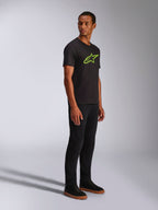 Alpinestars Ageless 2.0 CSF Tee, T-shirt met korte mouwen, zwart met felgroen Alpinestars-logo, gedragen met een zwarte broek en sneakers, casual op de motorsport geïnspireerde streetwear