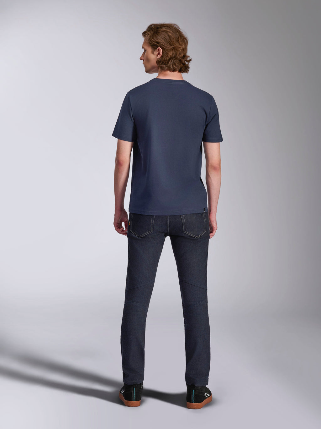 Alpinestars Ageless 2.0 CSF Tee, T-shirt met korte mouwen, marineblauw, achteraanzicht, gedragen door een man met donkere denim jeans en zwarte sneakers, casual motorsport-geïnspireerde streetwear