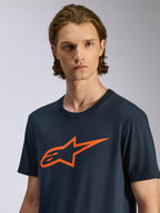 Alpinestars Ageless 2.0 CSF Tee, T-shirt met korte mouwen, marineblauw met oranje Alpinestars MX-helm art star-logo, casual streetwear geïnspireerd op de motorsport, man draagt het T-shirt