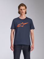 Alpinestars Ageless 2.0 CSF Tee, T-shirt met korte mouwen, marineblauw met oranje logo, MX-helmkunst op de voorzijde, casual motorsport-geïnspireerde streetwear, model draagt het shirt met een donkere jeans