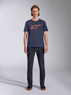 Alpinestars Ageless 2.0 CSF Tee, T-shirt met korte mouwen, donkerblauw met oranje Alpinestars-logo, gedragen door model met donkere jeans en sneakers, casual motorsport streetwear