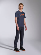 Alpinestars Ageless 2.0 CSF Tee, T-shirt met korte mouwen, marineblauw met oranje ster-logo, gedragen met donkere denim jeans en zwarte sneakers, casual motorsport-geïnspireerde streetwear