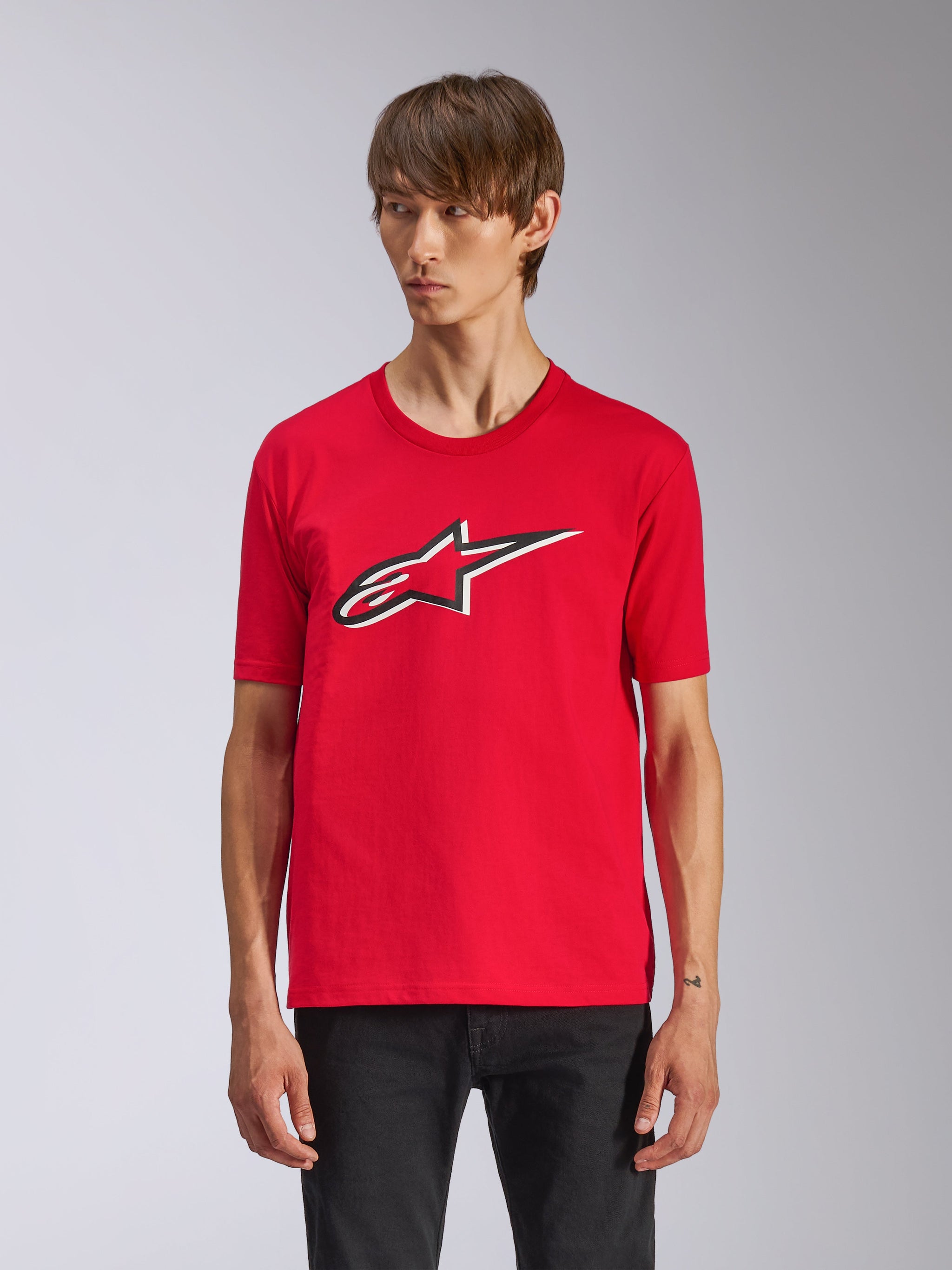 Alpinestars Ageless Shadow CSF Tee, Red Short Sleeve T-Shirt, featuring a front Ageless logo with black and white outlines, worn by a man with black pants, casual motorsport streetwear
