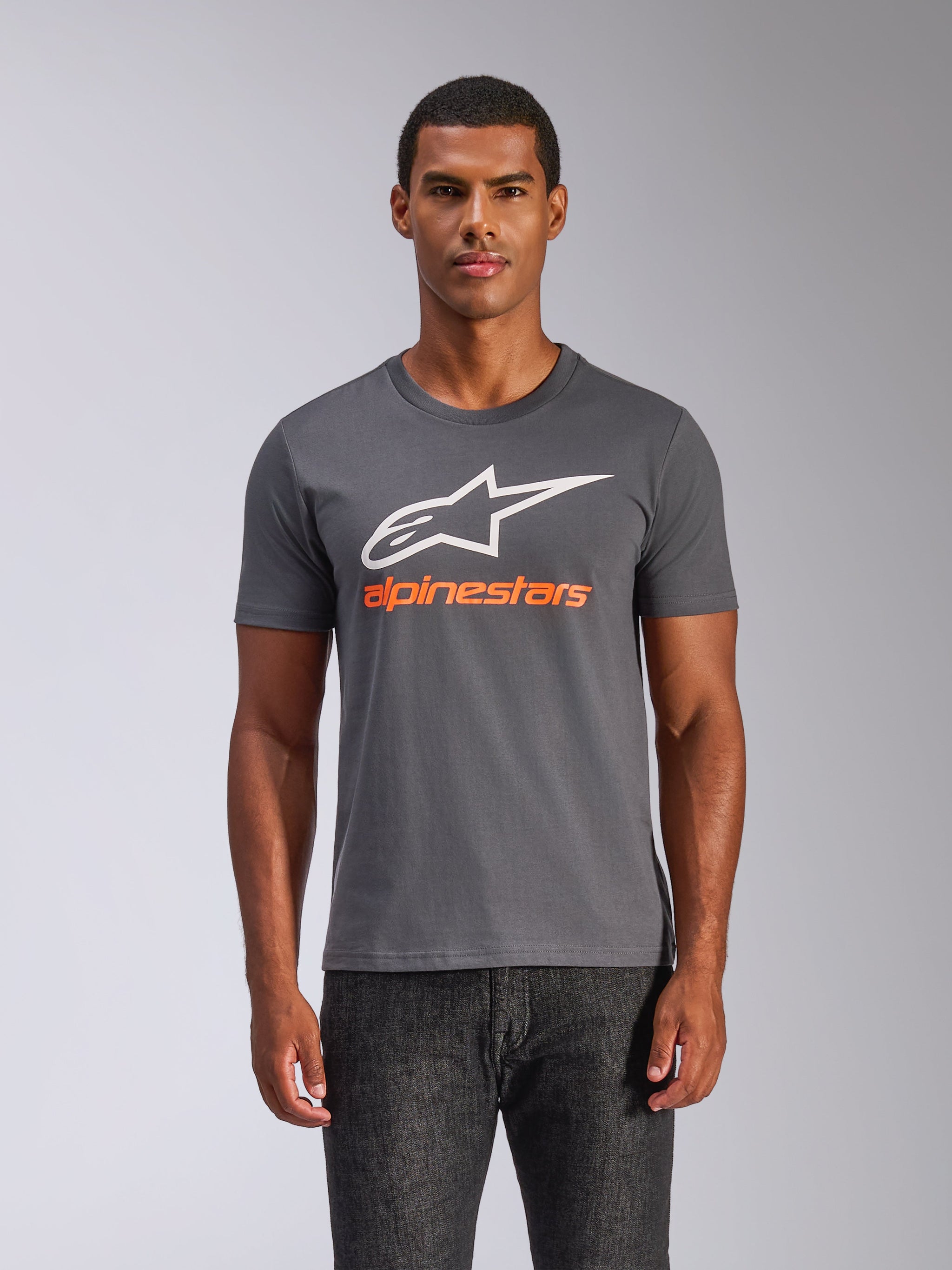 Alpinestars Always 2.0 CSF Tee, T-shirt met korte mouwen, antracietgrijs, groot wit A-star logo met oranje Alpinestars woordmerk, gedragen door een man, casual motorsport streetwear