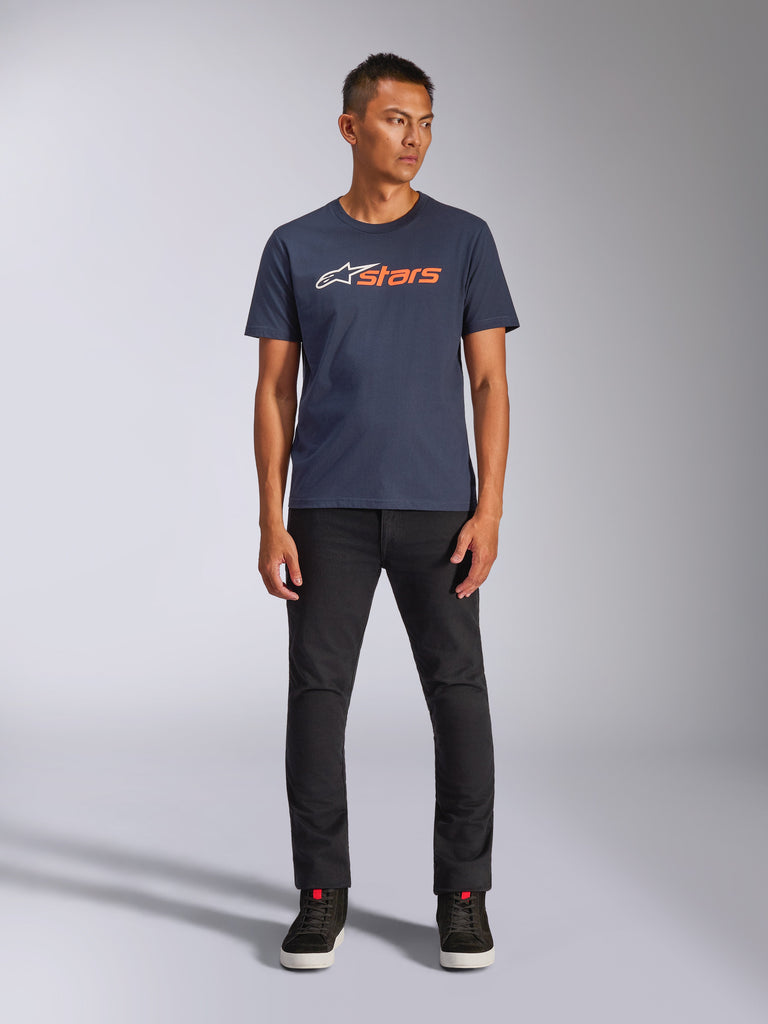 Alpinestars Blaze 2.0 CSF Tee, T-shirt met korte mouwen, marineblauw met wit en oranje Astars-logo, gedragen met zwarte broek en zwarte sneakers, casual motorsport-geïnspireerde streetwear