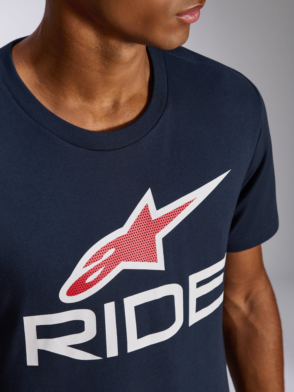 Alpinestars Ride 4.0 CSF Tee, T-shirt met korte mouwen, marineblauw, met een rood en wit sterlogo en grote witte 'RIDE' tekst, casual motorsport streetwear, close-up van een persoon die het shirt draagt
