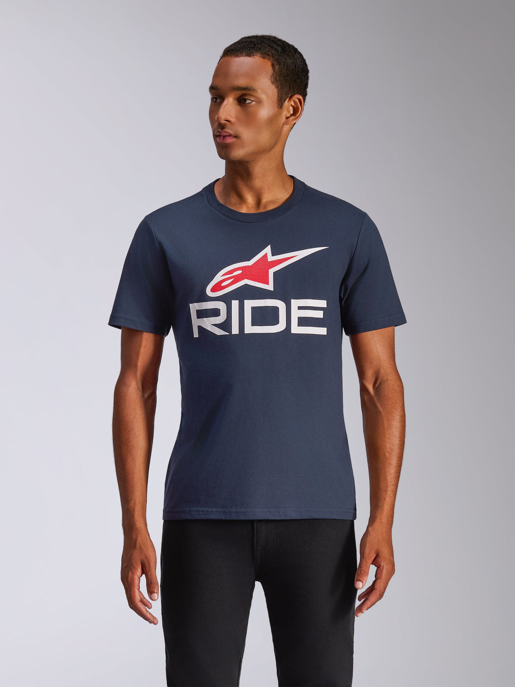 Alpinestars Ride 4.0 CSF Tee, T-shirt met korte mouwen, marineblauw met rood en wit Alpinestars-logo en witte RIDE-tekst, casual motorsport streetwear, man draagt het shirt op een zwarte broek