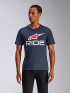 Alpinestars Ride 4.0 CSF Tee, T-shirt met korte mouwen, marineblauw met rood en wit Alpinestars-logo en witte RIDE-tekst, casual motorsport streetwear, man draagt het shirt op een zwarte broek