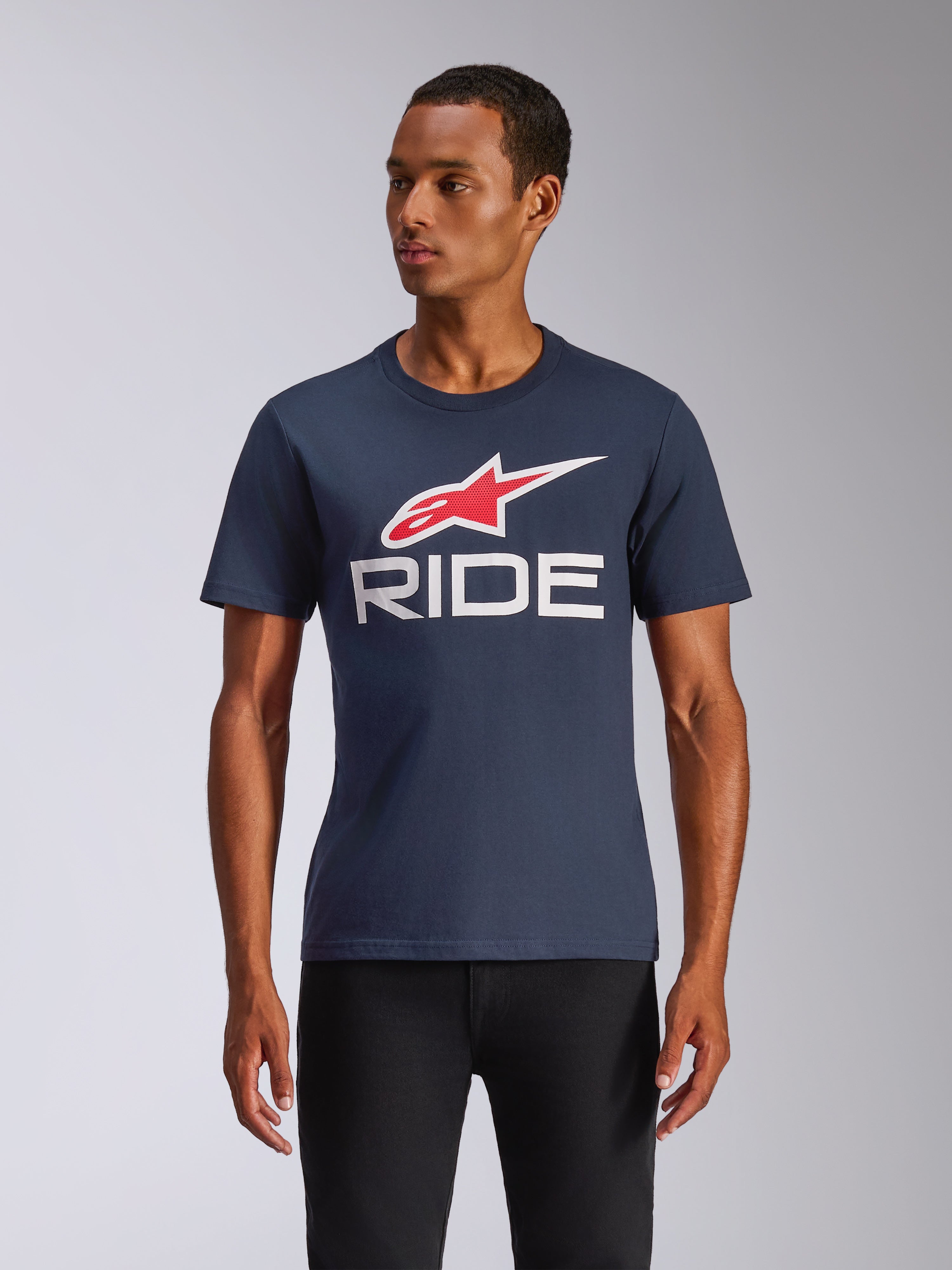 Alpinestars Ride 4.0 CSF Tee, T-shirt met korte mouwen, marineblauw met rood en wit Alpinestars-logo en witte RIDE-tekst, casual motorsport streetwear, man draagt het shirt op een zwarte broek