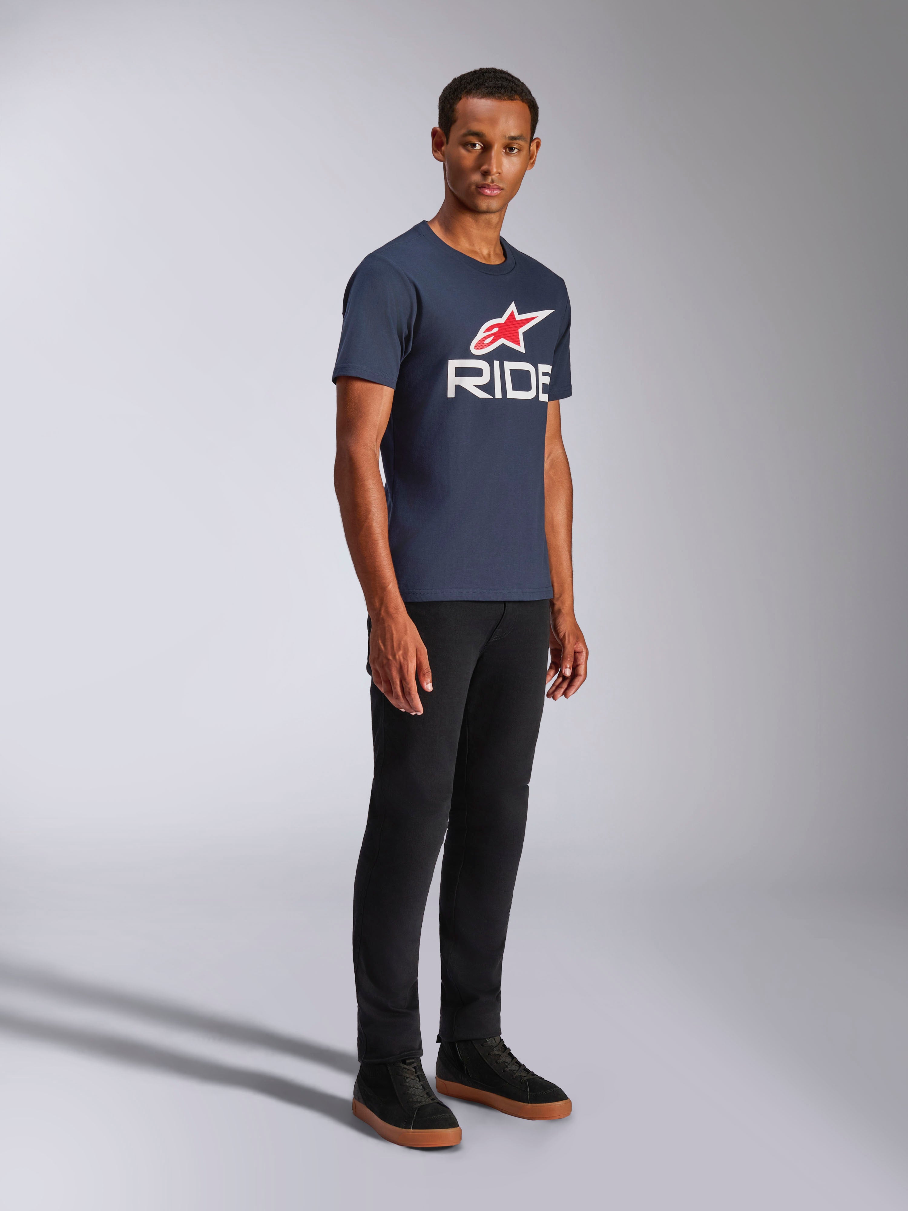 Alpinestars Ride 4.0 CSF Tee, T-shirt met korte mouwen, donkerblauw, wit RIDE-logo met rode Alpinestars-ster, gedragen door een model met zwarte broek en sneakers, casual motorsport lifestyle kleding
