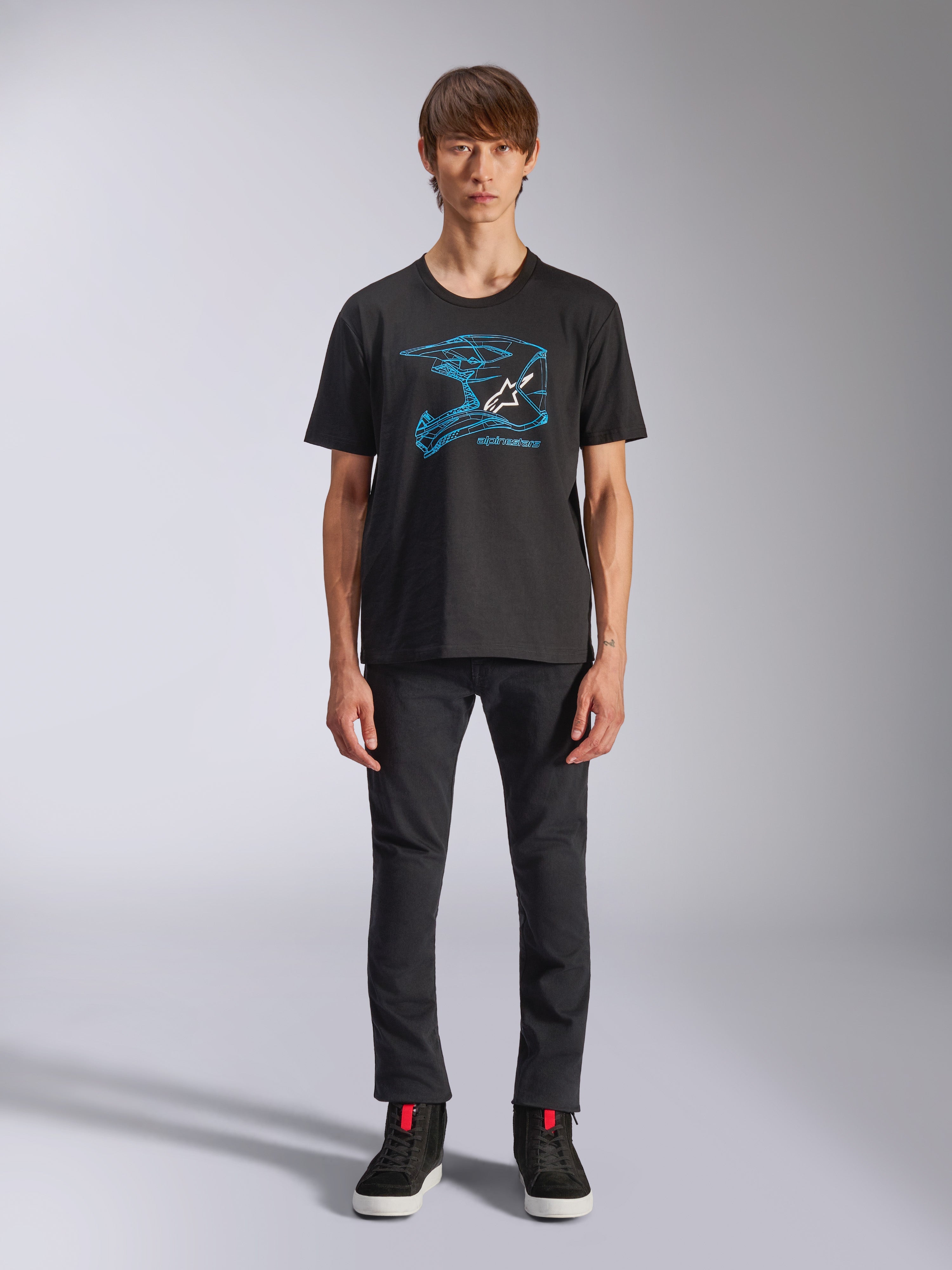 Alpinestars CSF Tee, T-shirt met korte mouwen, zwart, blauwe motorcrosshelm-graphic met wit logo, gedragen door een model met een zwarte broek en zwarte sneakers, casual motorsport-geïnspireerde streetwear