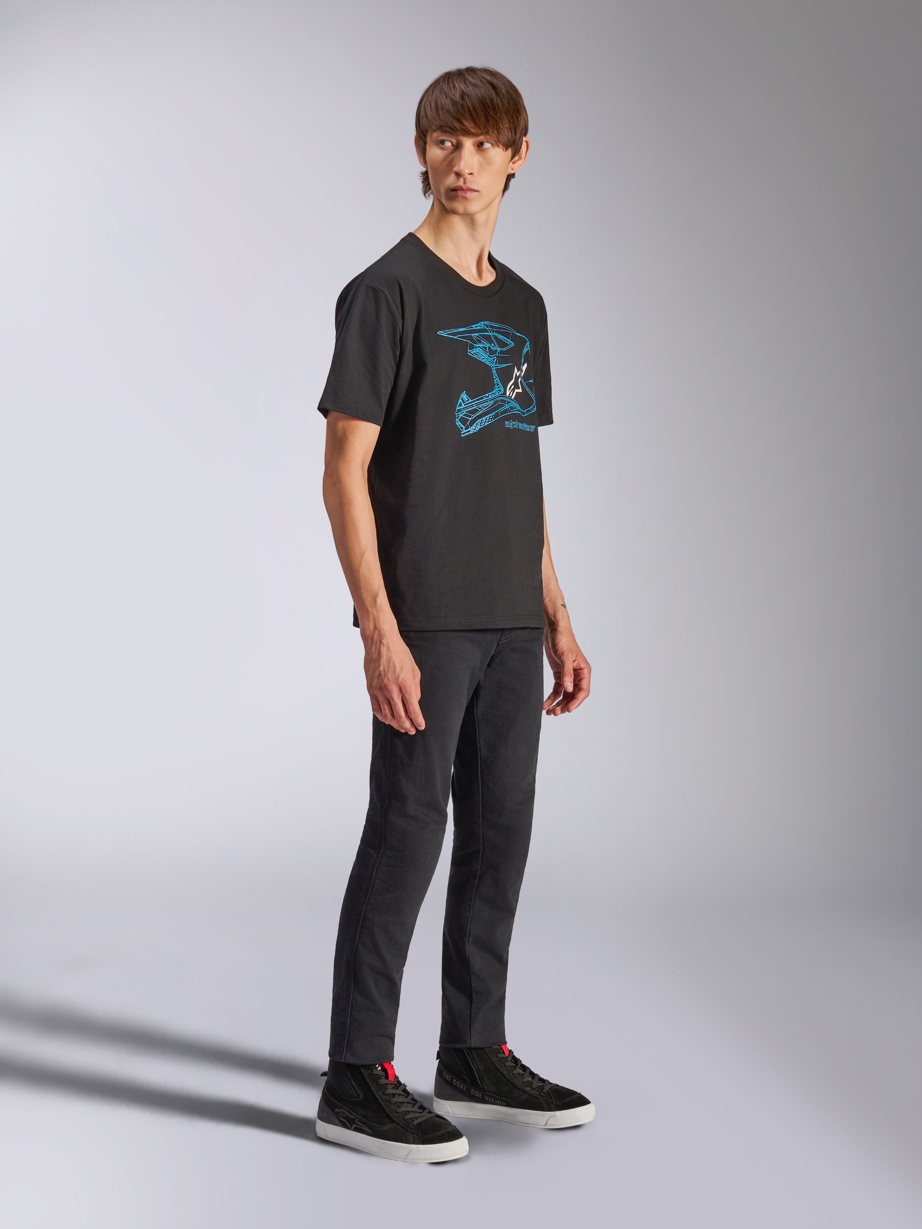 Alpinestars CSF Tee, zwart T-shirt met korte mouwen met blauwe MX helm graphic, gedragen door model met zwarte broek en hoge sneakers, casual motorsport streetwear