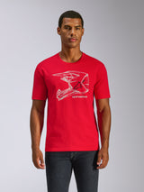 Alpinestars CSF Tee, T-shirt met korte mouwen, rood, witte grafische MX-helm print op de borst, casual motorsport streetwear, model draagt rood shirt met donkere broek