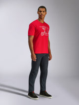 Alpinestars CSF Tee, T-shirt met korte mouwen, rood, witte MX-helm graphic, gedragen door model met donkere denim jeans en zwarte sneakers, casual motorsport streetwear