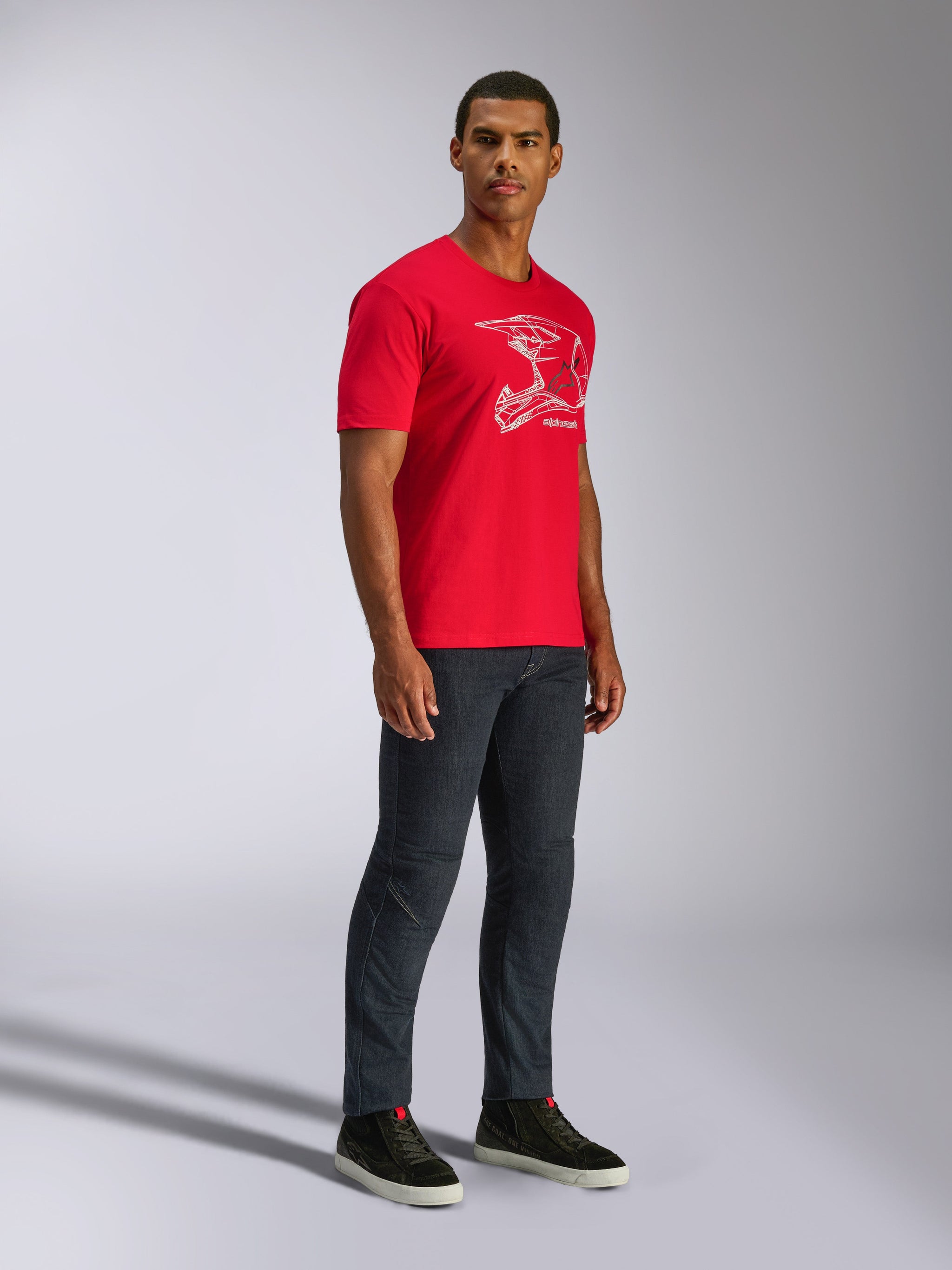 Alpinestars CSF Tee, T-shirt met korte mouwen, rood, witte MX-helm graphic, gedragen door model met donkere denim jeans en zwarte sneakers, casual motorsport streetwear