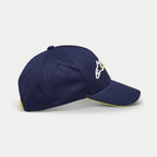 Alpinestars Par pet, donkerblauwe baseballpet, zijaanzicht met wit en geel geborduurd logo, gebogen klep met gele sandwich-bies, casual gestructureerde pet