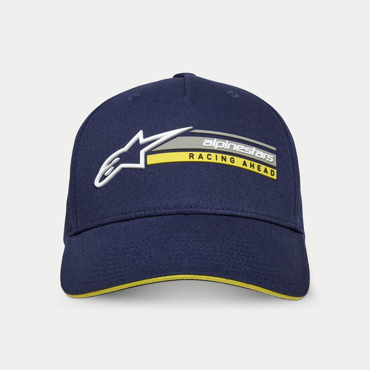Alpinestars Par Hat, marineblauw, gestructureerde snapback cap met gebogen klep, voorzien van 3D wit Astars-logo en 'alpinestars RACING AHEAD' graphic in grijs en geel, geel sandwich-accent op de klep, casual motorsport streetwear