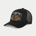 Alpinestars Heritage Patch Trucker Hat, zwart, gestructureerde kroon met gebogen klep, grote geborduurde heritage patch op de voorzijde met gevleugeld wiel en 'Racing Ahead Est. 1963', zwarte mesh panelen aan de achterkant met sterlogo aan de zijkant, casual motorsport lifestyle hoofdbedekking