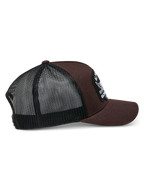 Alpinestars Heritage Patch Trucker pet, bruin en zwart, gestructureerde kroon met een grote geborduurde patch, gebogen klep, zwarte mesh achterkant, casual motorsport-geïnspireerd ontwerp