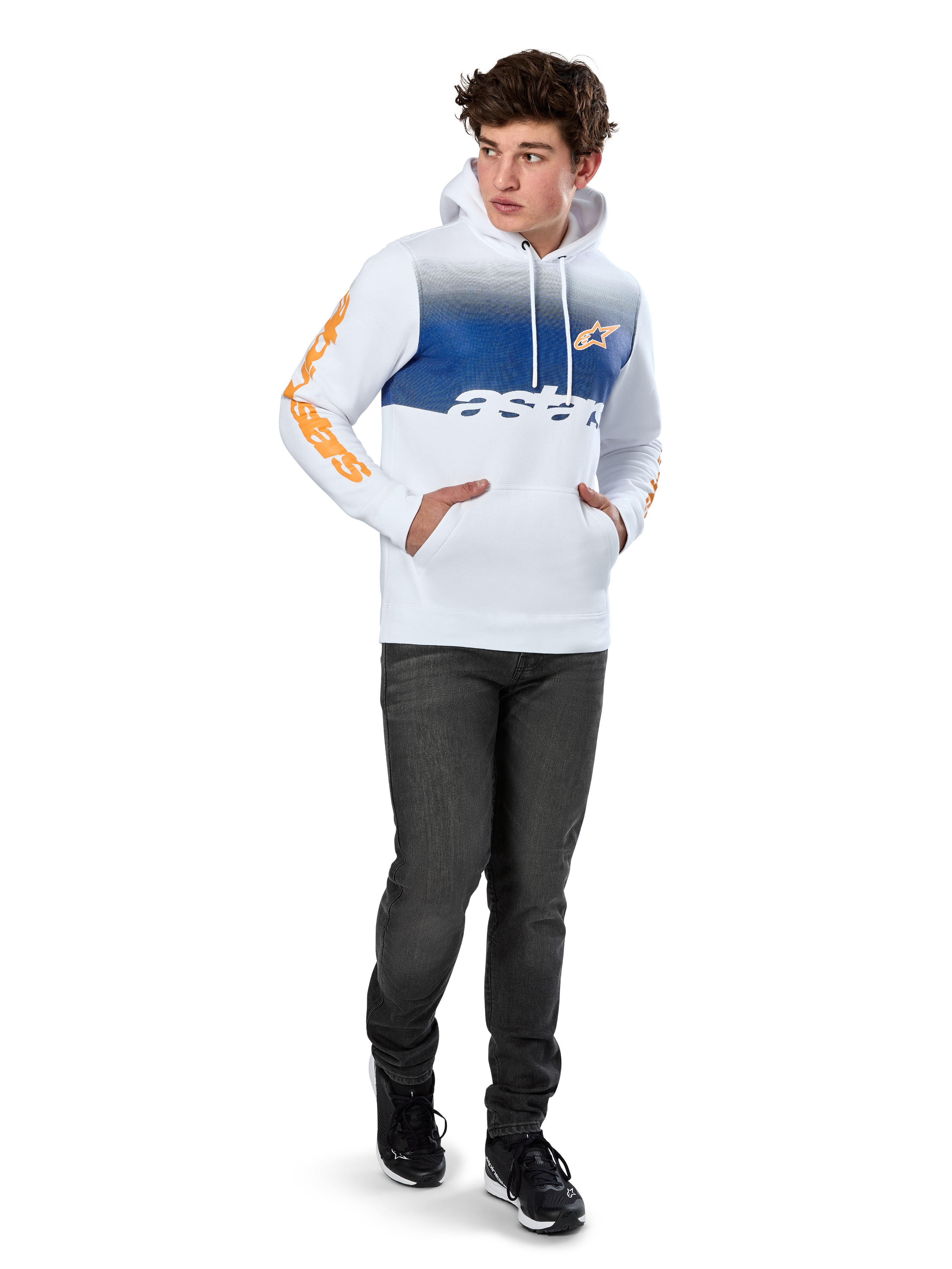 Alpinestars Specter Hoodie, witte pullover fleece met blauwe kleurverloop-print, oranje HD-logo op de borst en woordmerken op de mouwen, voorzien van een kangoeroezak en capuchon met trekkoord, gedragen met donkere jeans voor een casual motorsport-geïnspireerde look