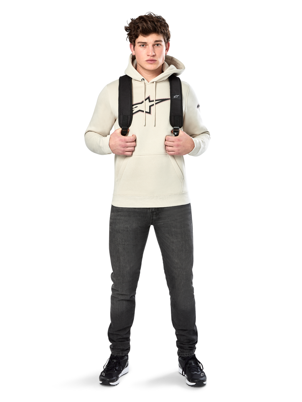 Alpinestars Insignia Hoodie, casual streetwear, Off White fleece pullover, logo met carbonlook en rode omtrek, capuchon met trekkoord, kangoeroezak, gedragen door model met zwarte rugzak en donkergrijze jeans