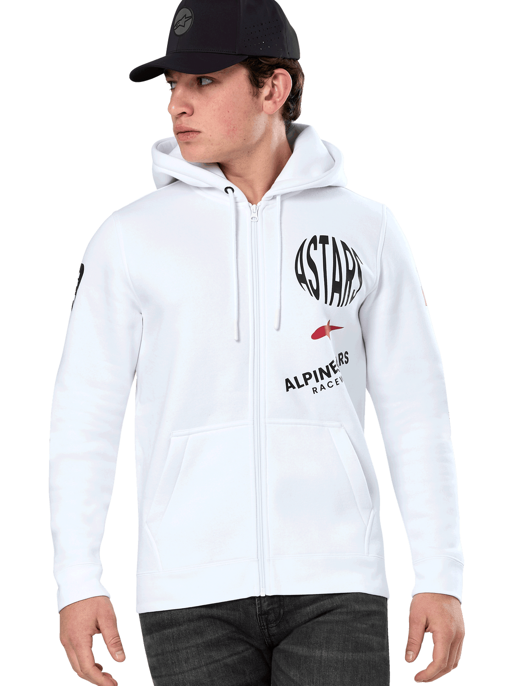 Alpinestars Variegate hoodie, witte ritshoodie met zwarte en rode ASTARS racing graphics, gedragen door een model met een zwarte pet en donkere jeans, casual motorsport streetwear met kangoeroezak en capuchon met trekkoord