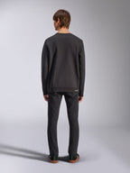 Alpinestars Positive Crew, zwarte pullover sweatshirt, achteraanzicht op mannelijk model, gedragen met zwarte jeans en casual sneakers, voorzien van geribde manchetten en zoom, op motorsport geïnspireerde streetwear
