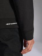 Alpinestars Positive Crew, zwarte pullover sweatshirt, detailopname van de geribbelde zoom en mouwboord met wit Alpinestars-logo, hoogwaardige stoftextuur, casual op motorsport geïnspireerde sportkleding