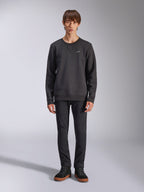 Alpinestars Positive Crew sweatshirt, casual zwarte sweater met ronde hals, klein wit logo op de borst, V-stiksel bij de halslijn, studio-opname van model in zwarte broek en sneakers, lifestylekleding geïnspireerd op de motorsport
