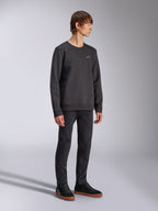Alpinestars Positive Crew, pullover sweatshirt, zwart, klein wit Alpinestars-logo op de borst, geribbelde kraag met V-stikseldetail, geribbelde manchetten en zoom, gedragen door een model met zwarte broek en sneakers, casual motorsport-geïnspireerde streetwear