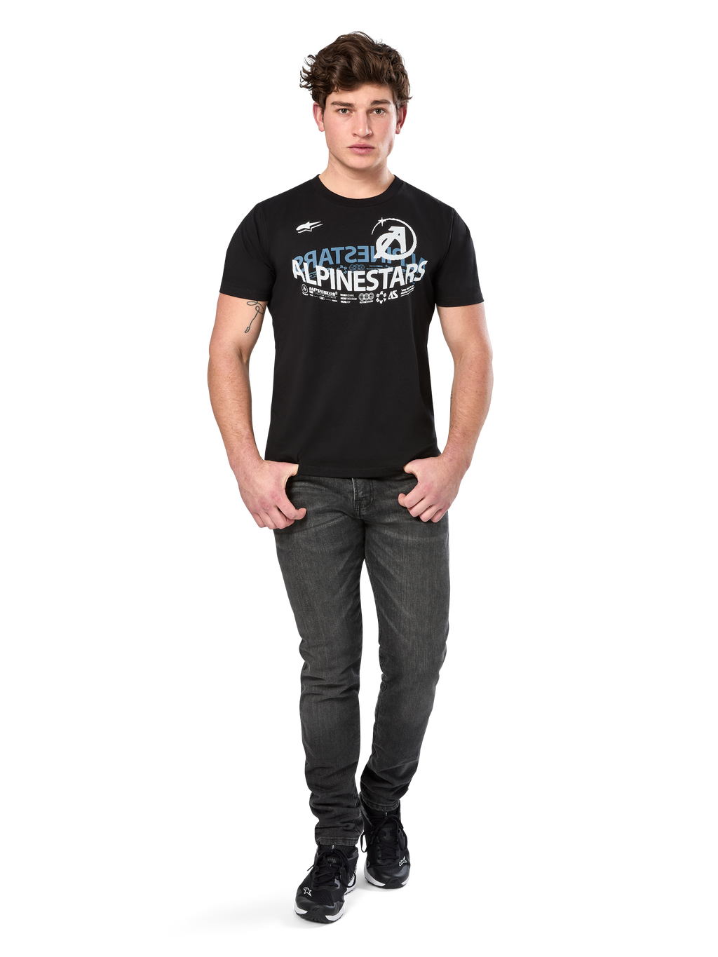 Alpinestars Semicircle CSF Tee, T-shirt met korte mouwen, zwart, wit en lichtblauw gebogen grafisch ontwerp op de borst, gedragen door model met donkergrijze jeans en zwarte sneakers, casual motorsport streetwear