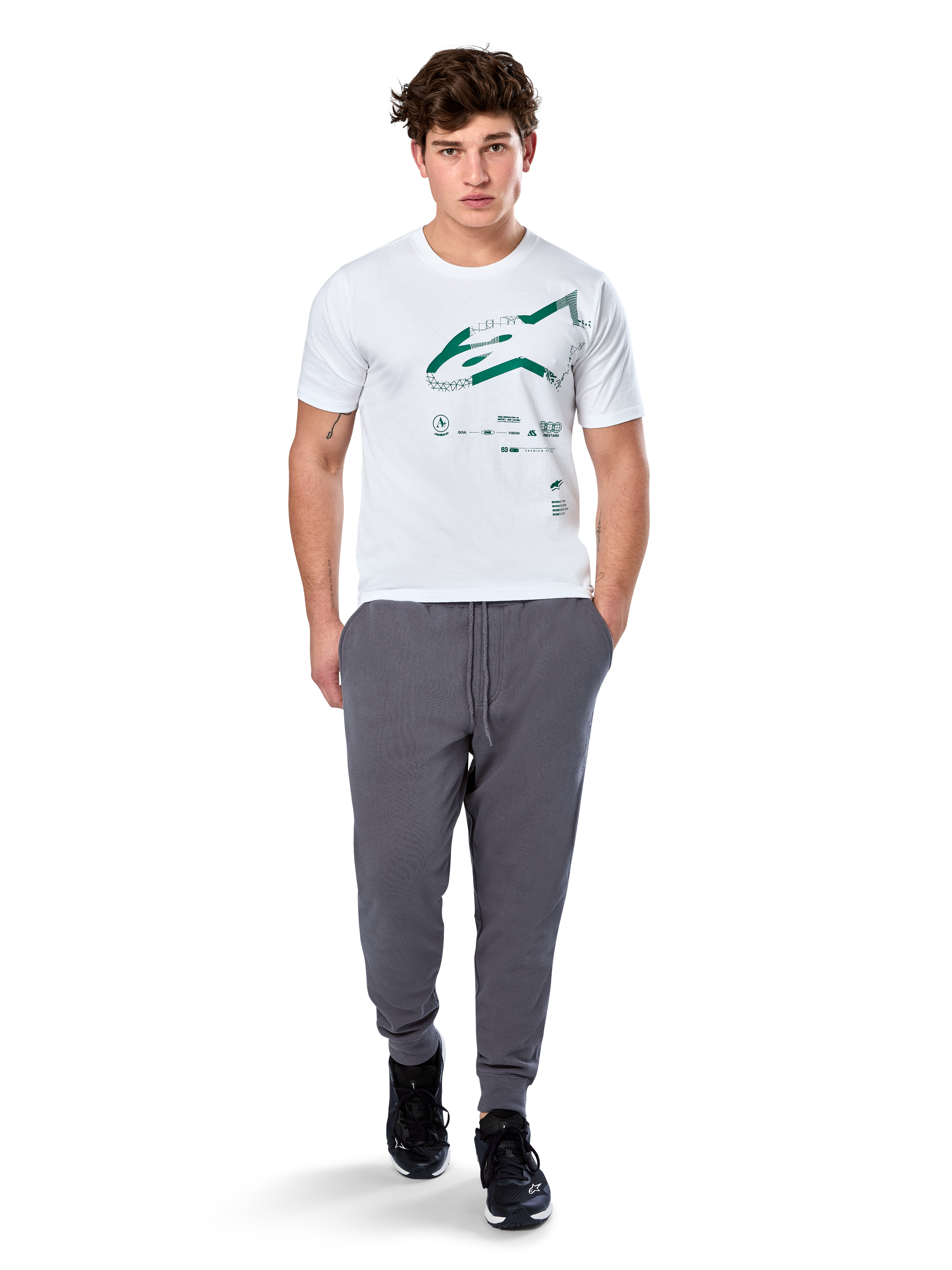 Alpinestars Geografica CSF Tee, T-shirt met korte mouwen, wit, groen Astars-logo met geografische multi-tech graphic, gedragen met grijze joggingbroek en zwarte sneakers, casual motorsport streetwear