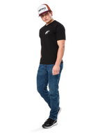 Alpinestars Formulate Csf Tee, T-shirt met korte mouwen, zwart met wit Astars-logo op de borst, gedragen door een model met blauwe jeans, een bordeauxrode en witte pet en zwarte sneakers, casual motorsport-geïnspireerde streetwear